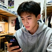 一位20多岁的大学生男性头像，穿着连帽卫衣，手拿手机显示比分页面，背景是大学宿舍。